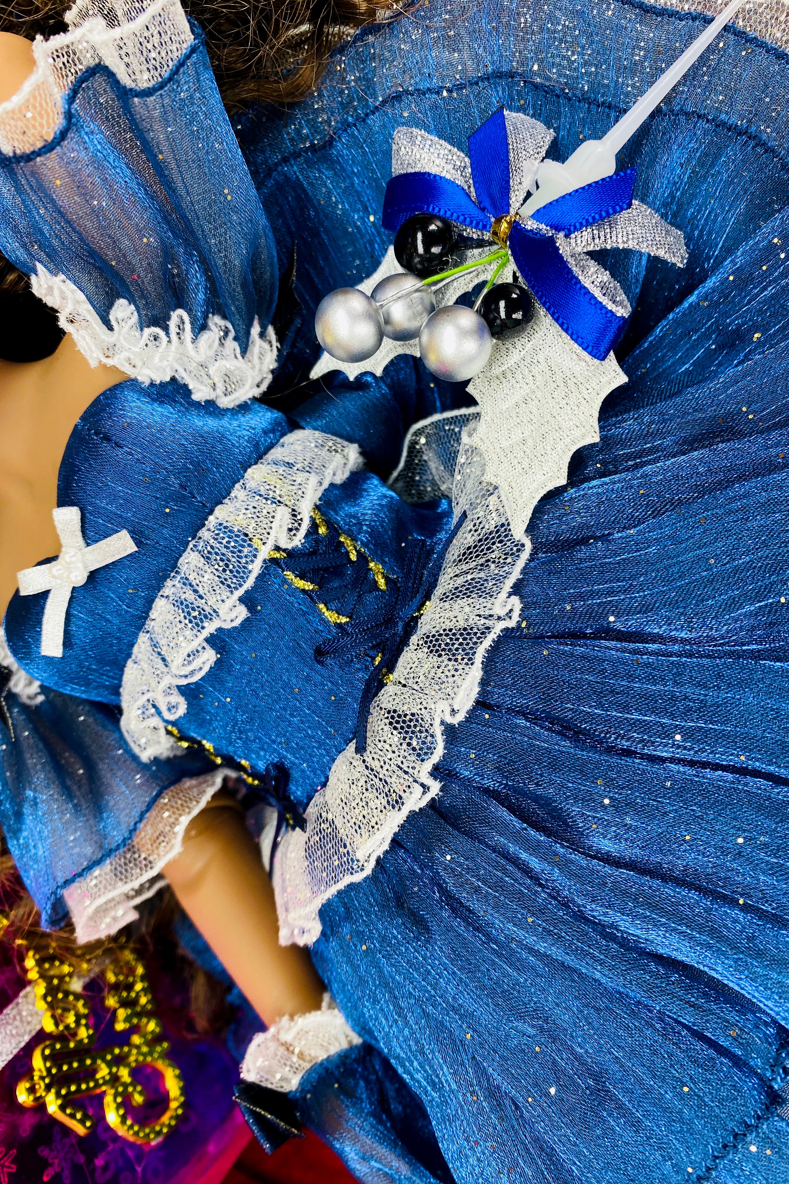 Close-up of a blue dress with white lace details and decorative elements.