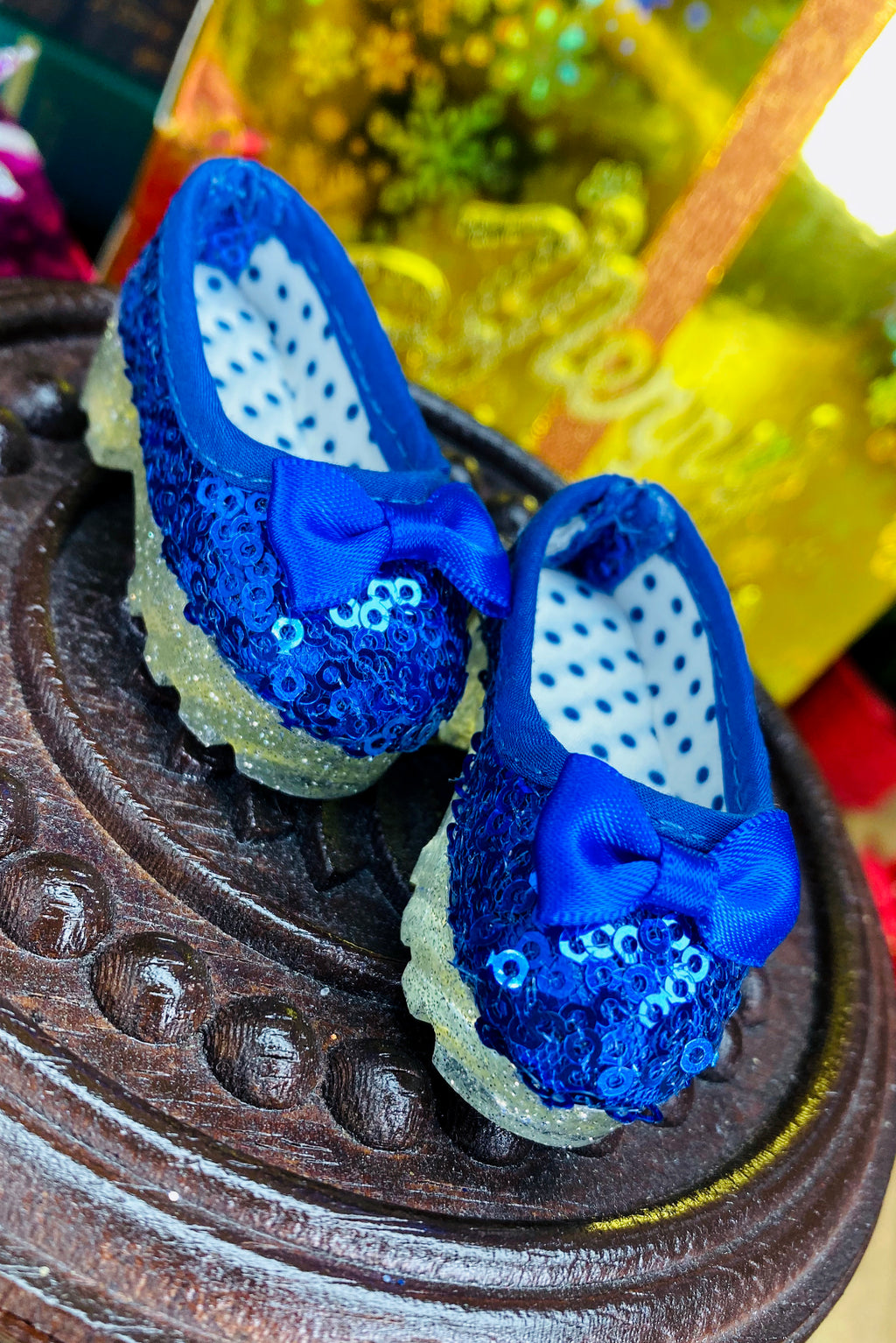 Pair of blue sequin shoes with white polka dots on a decorative surface.