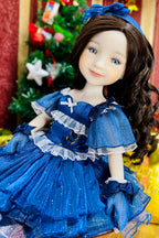 Doll in a blue dress with a Christmas tree in the background