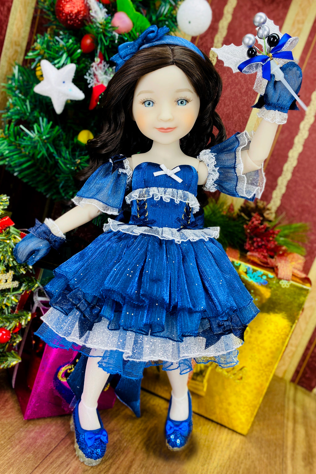 Doll in a blue dress with a Christmas tree and presents in the background