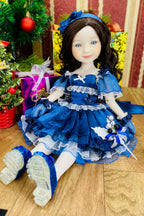 Doll in a blue dress with decorative elements on a wooden floor.