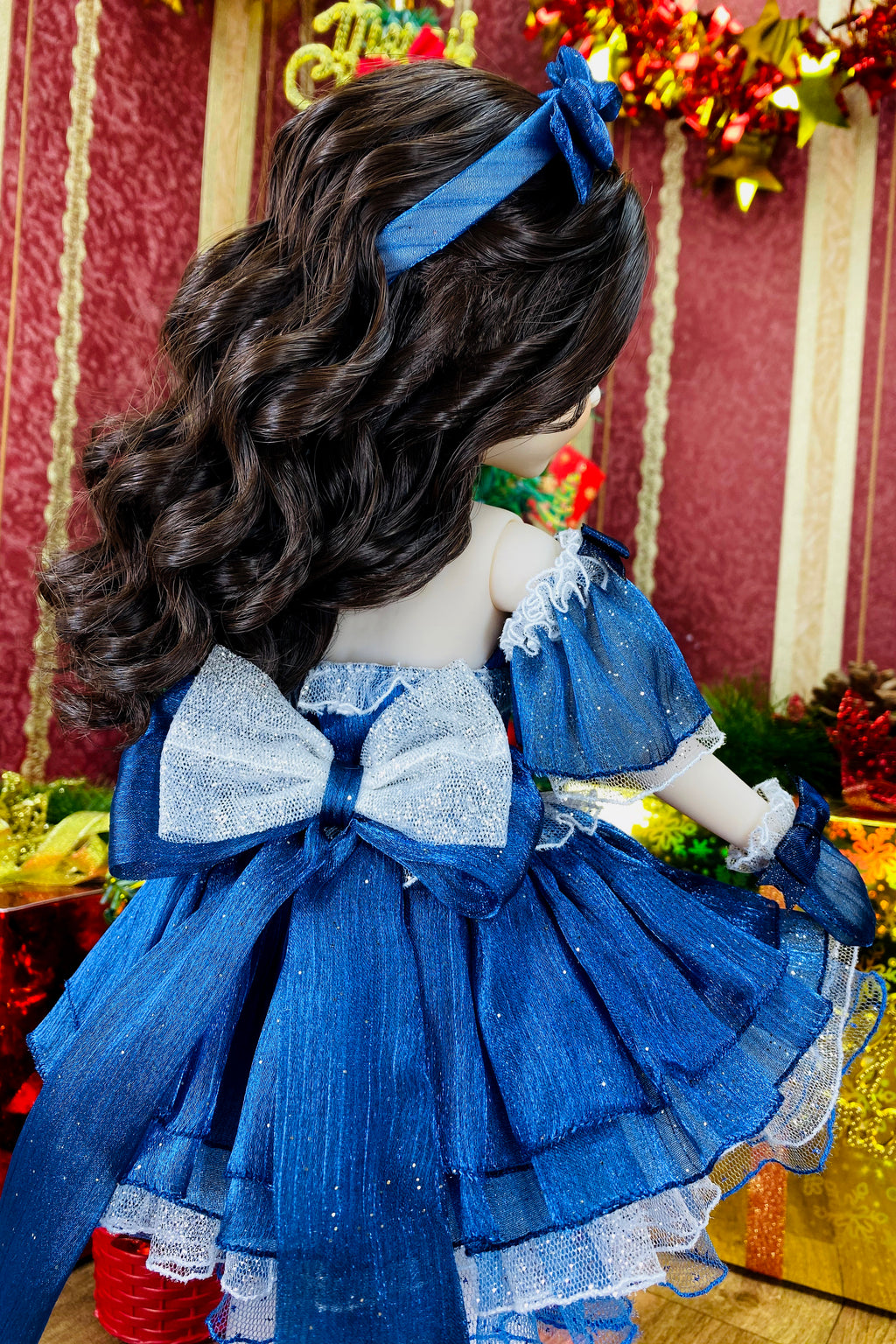 Doll with blue dress and hair accessory against a festive background