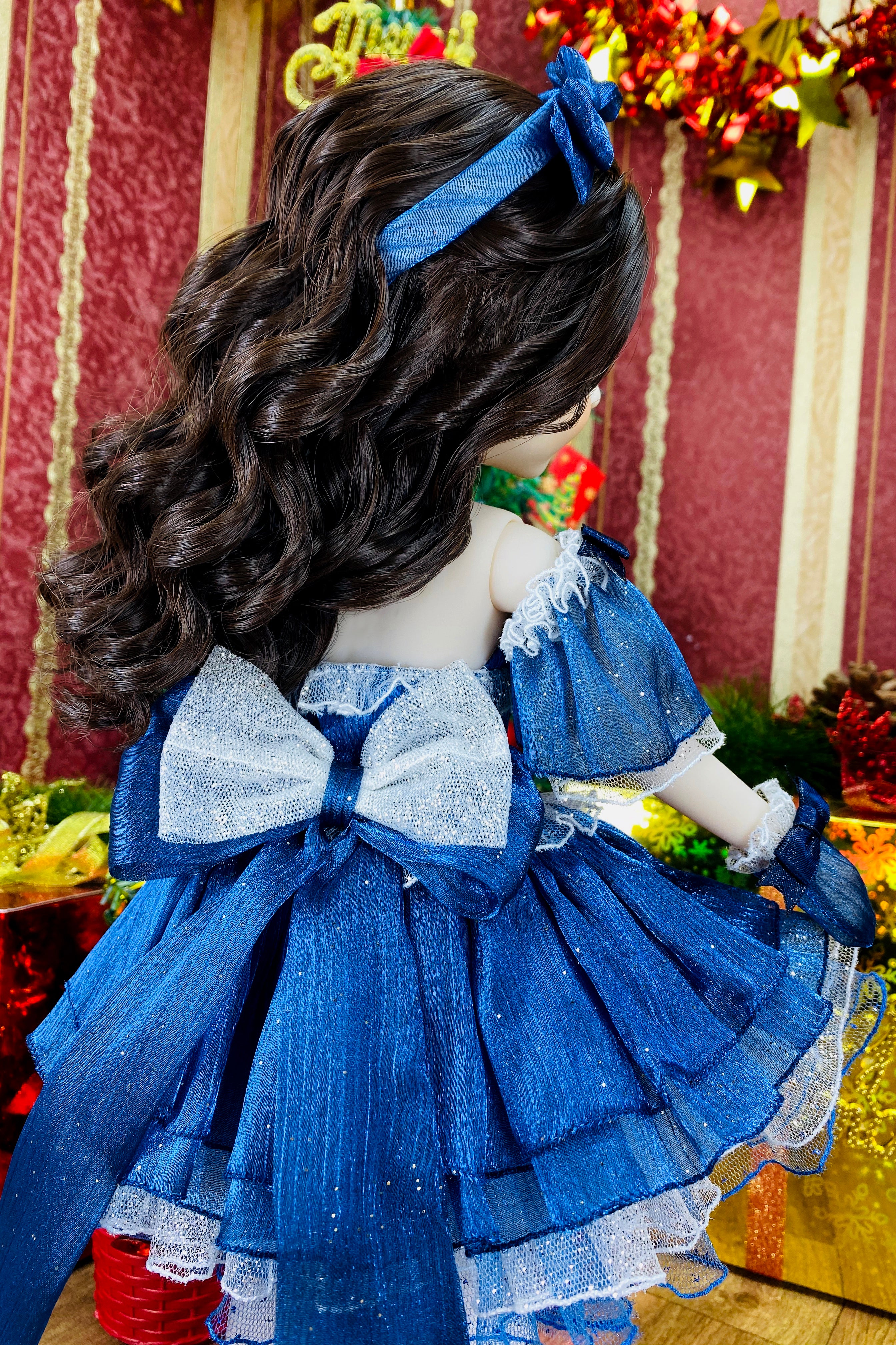 Doll with blue dress and hair accessory against a festive background