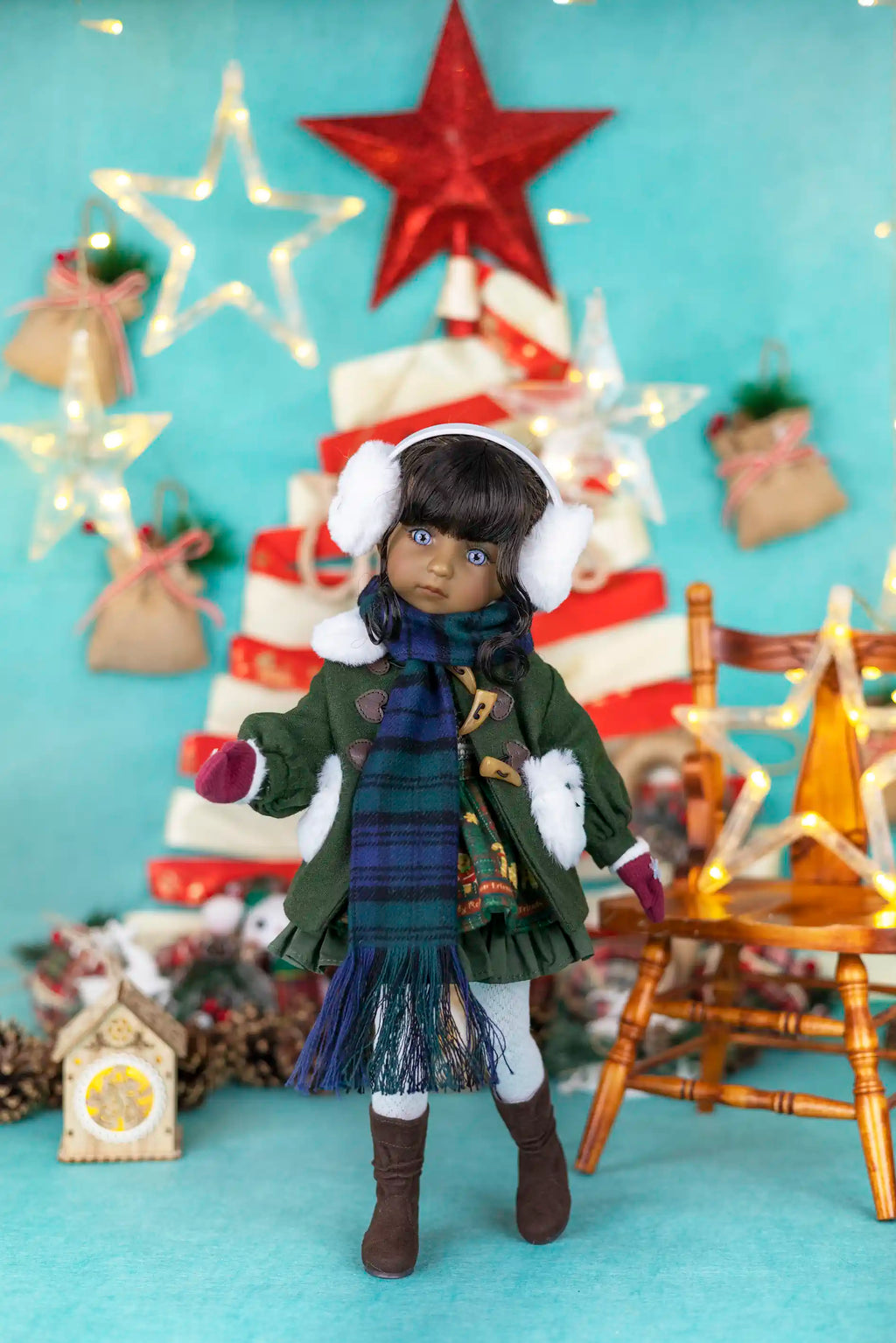 Doll in winter clothing with a Christmas tree and decorations in the background