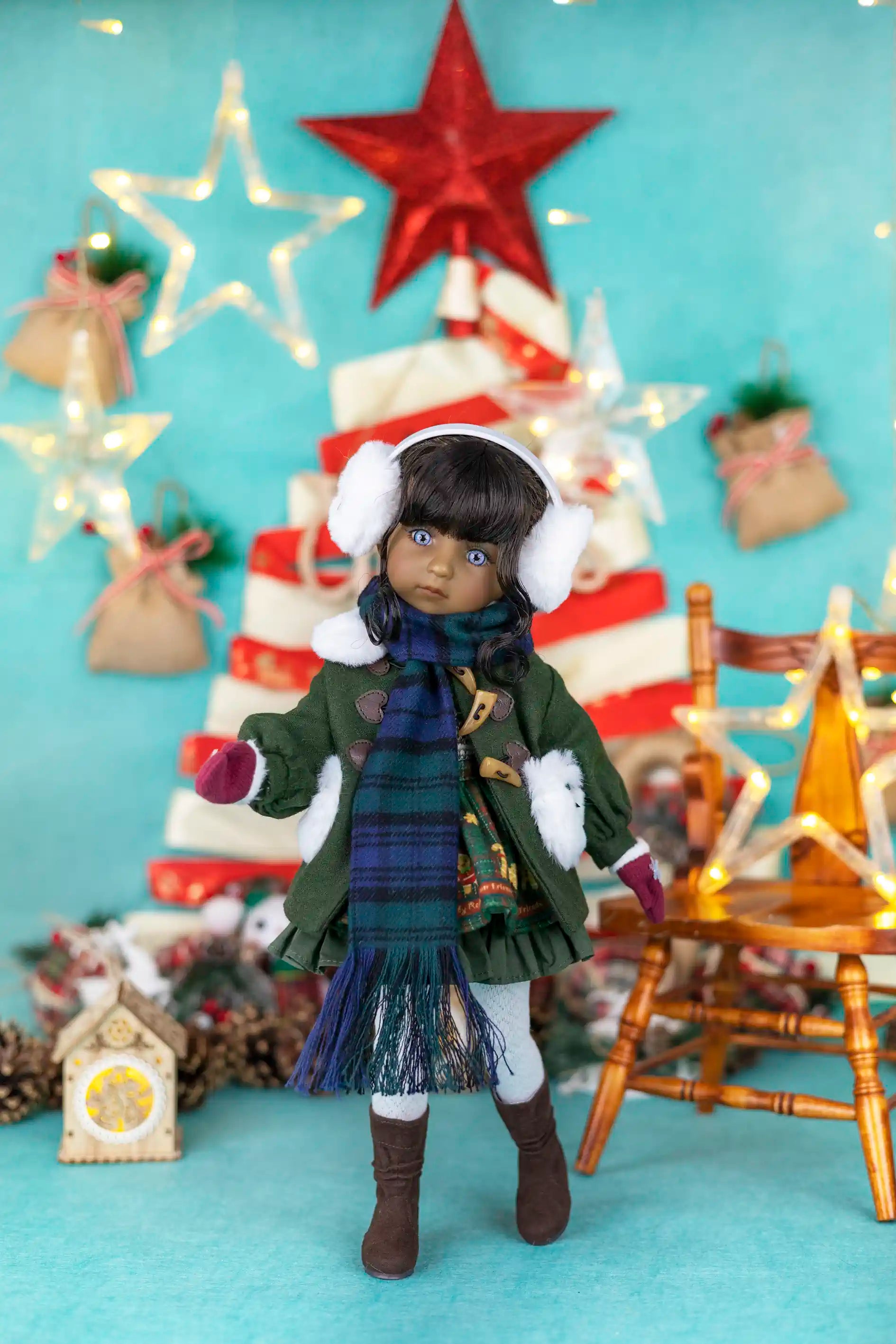 Doll in winter clothing with a Christmas tree and decorations in the background