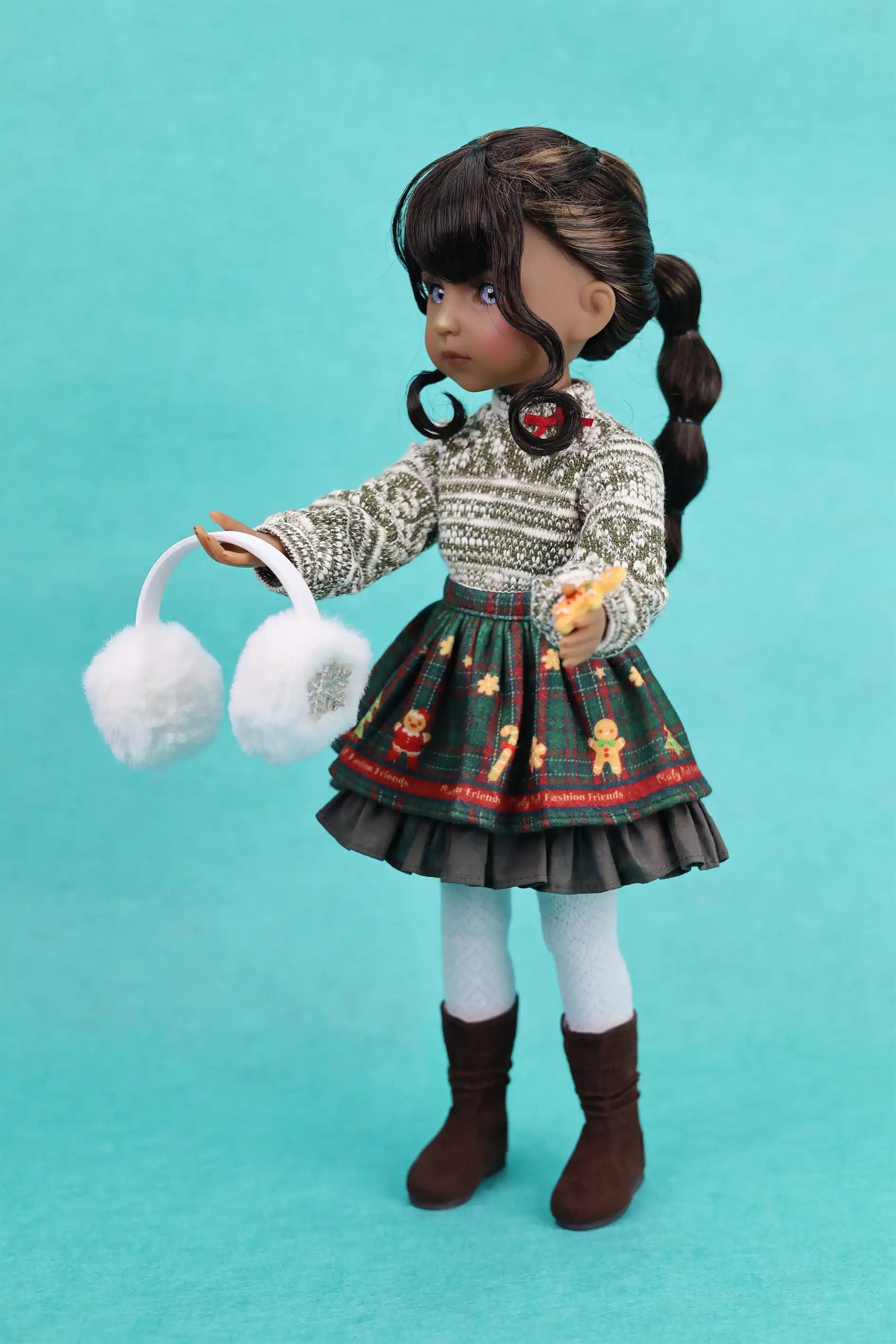 Doll wearing a patterned sweater and skirt with white gloves on a teal background