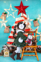 Doll in a festive setting with Christmas decorations and lights.