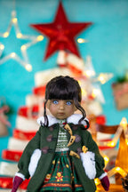 Doll in a festive outfit with a Christmas tree and star in the background