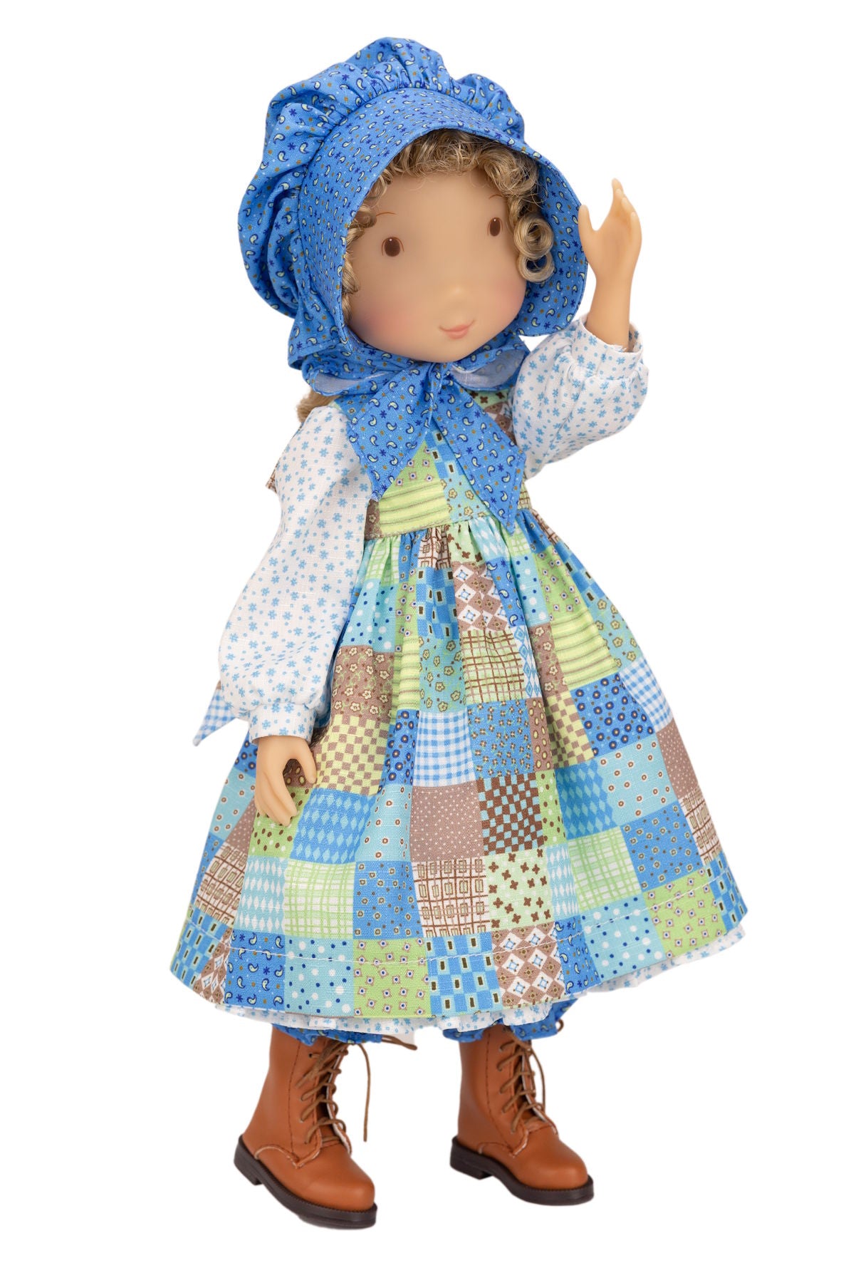 Holly Hobbie Doll wearing a patchwork dress and blue bonnet on a white background