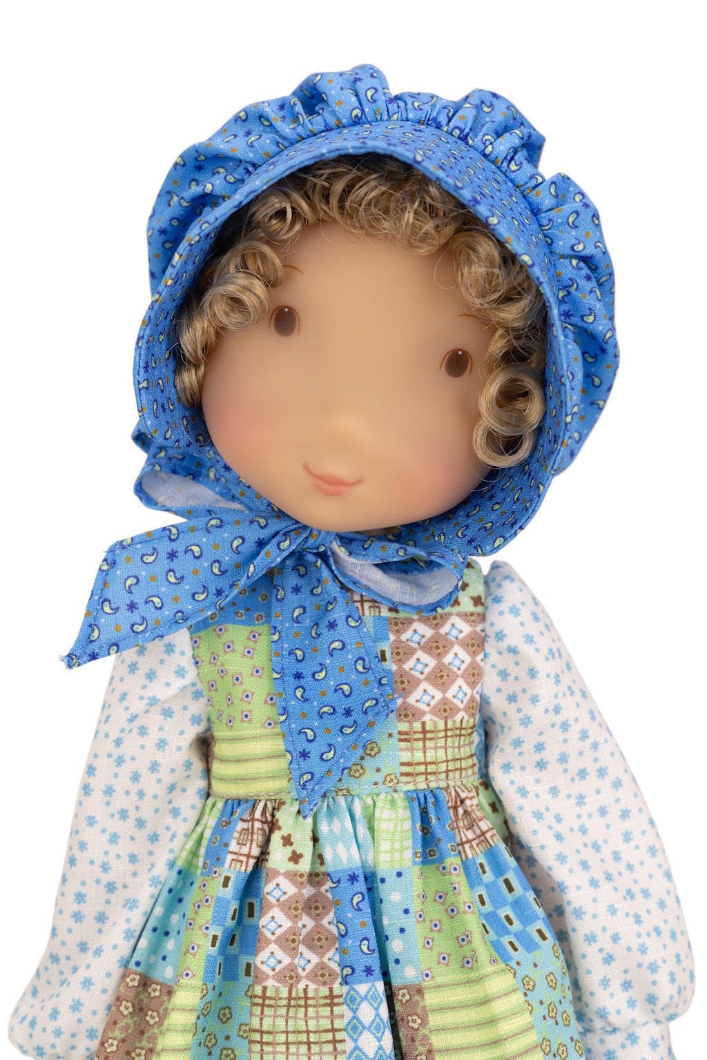 Holly Hobbie Doll wearing a blue patterned bonnet and colorful dress on a white background