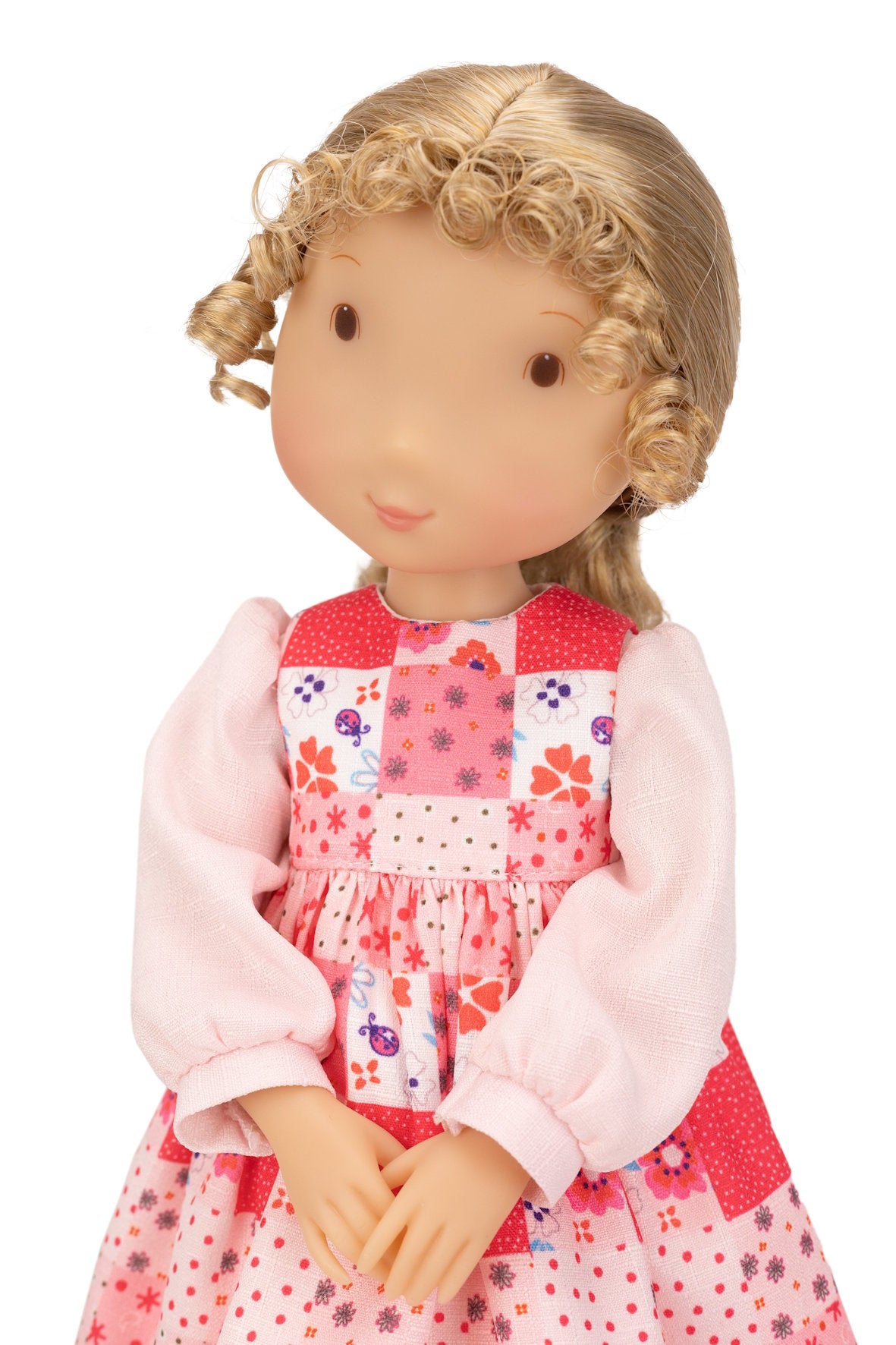 Holly Hobbie Doll with blonde hair wearing a pink dress with floral patterns on a white background