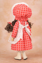 A Holly Hobbie doll viewed from the back wearing a red and white gingham dress with a white lace apron, matching bonnet, and white boots, set against a warm beige background.