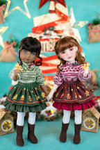 Two dolls in festive outfits standing against a decorated background with Christmas elements.