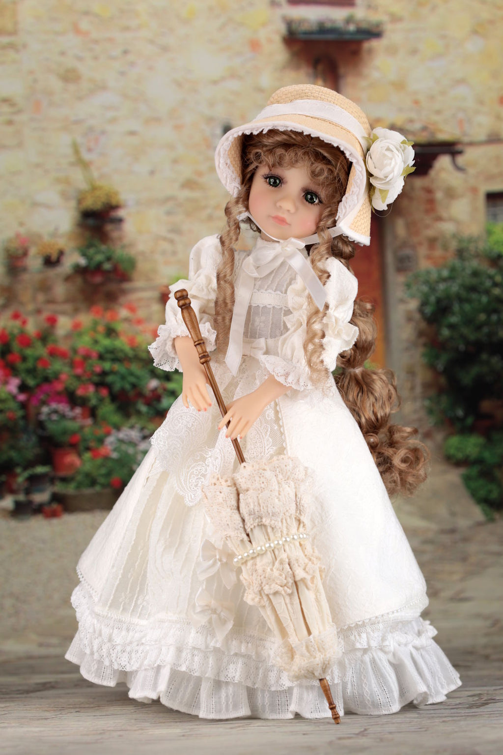 Vintage-style doll in a white dress with a bonnet, holding a parasol, against a rustic outdoor background.