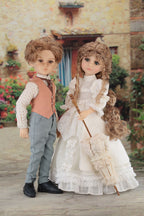 Two dolls, a boy and a girl, standing together in an outdoor setting with flowers and a building in the background.