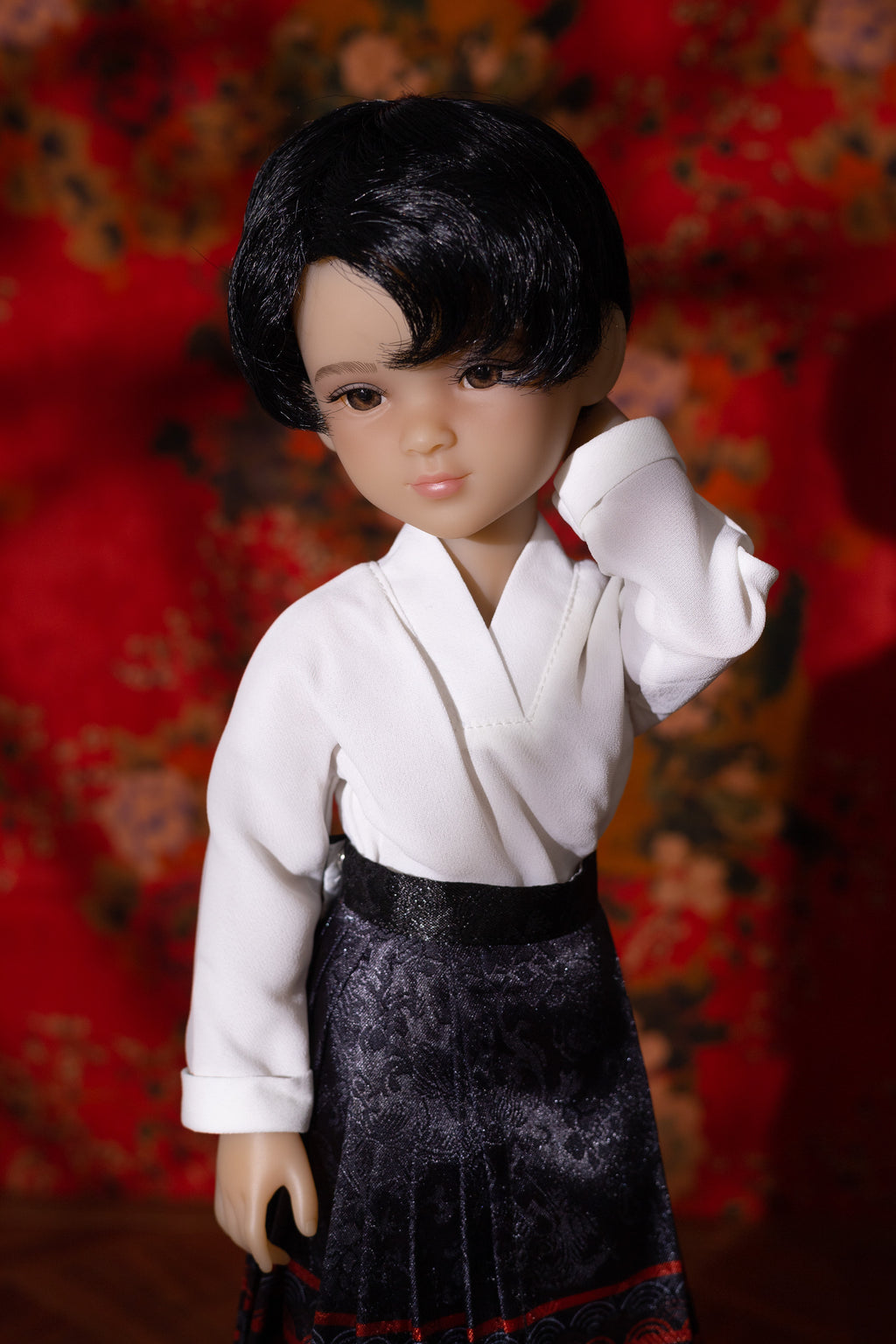 Doll wearing a white shirt and black skirt against a red floral background