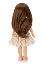 Doll with long brown hair and a floral skirt on a white background
