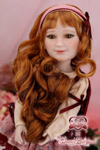 Doll with long red hair and a pink headband on a pink background