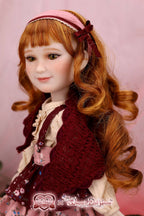 Doll with red hair and vintage outfit against a pink background