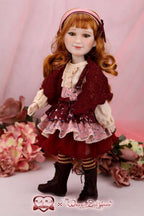 Doll with red hair and vintage outfit surrounded by flowers on a pink background