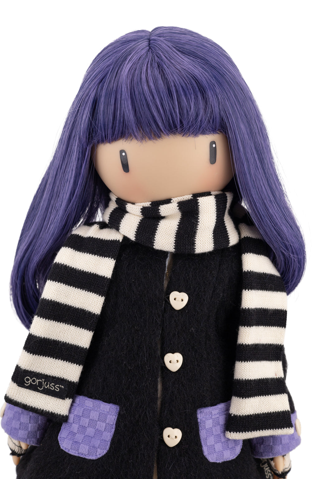 Doll with purple hair and a black and white striped scarf wearing a black coat.