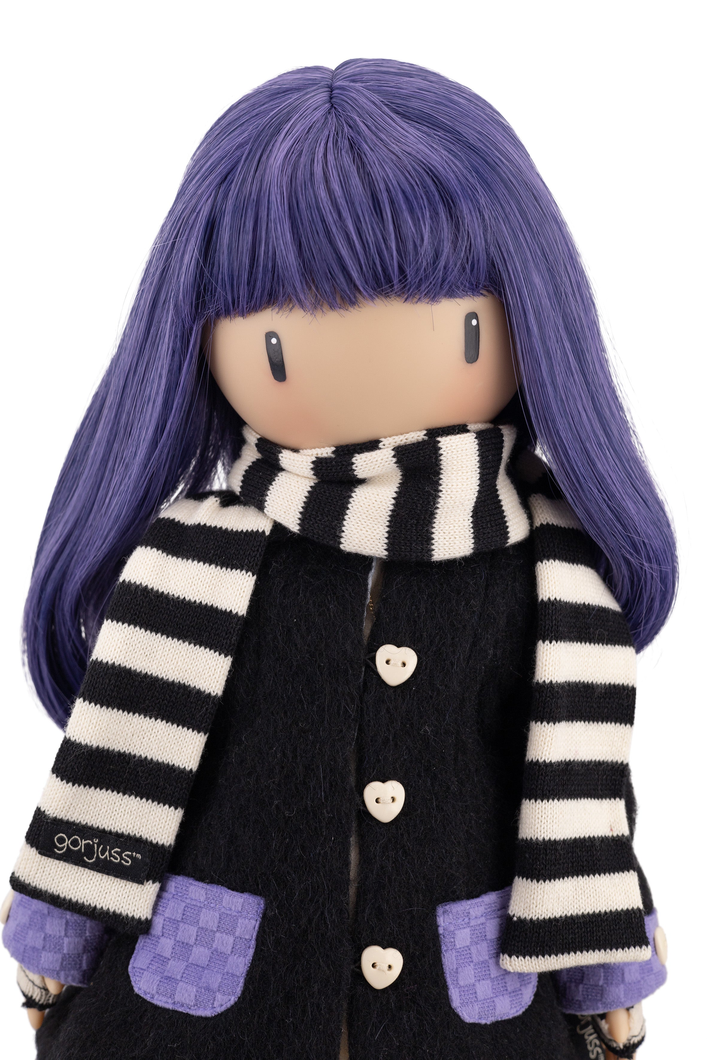 Doll with purple hair and a black and white striped scarf wearing a black coat.