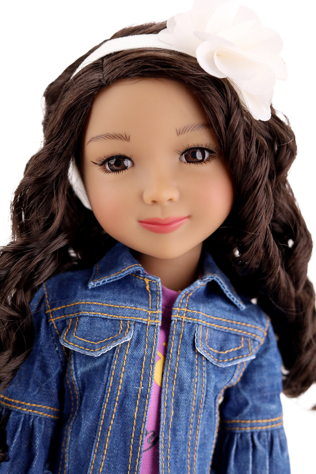 Doll with long brown hair wearing a denim jacket and white headband on a white background