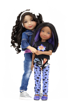 Kayla and Kelsey with long hair, one wearing a denim jacket and jeans, the other in a black top and blue pants with butterfly pattern, on a white background.