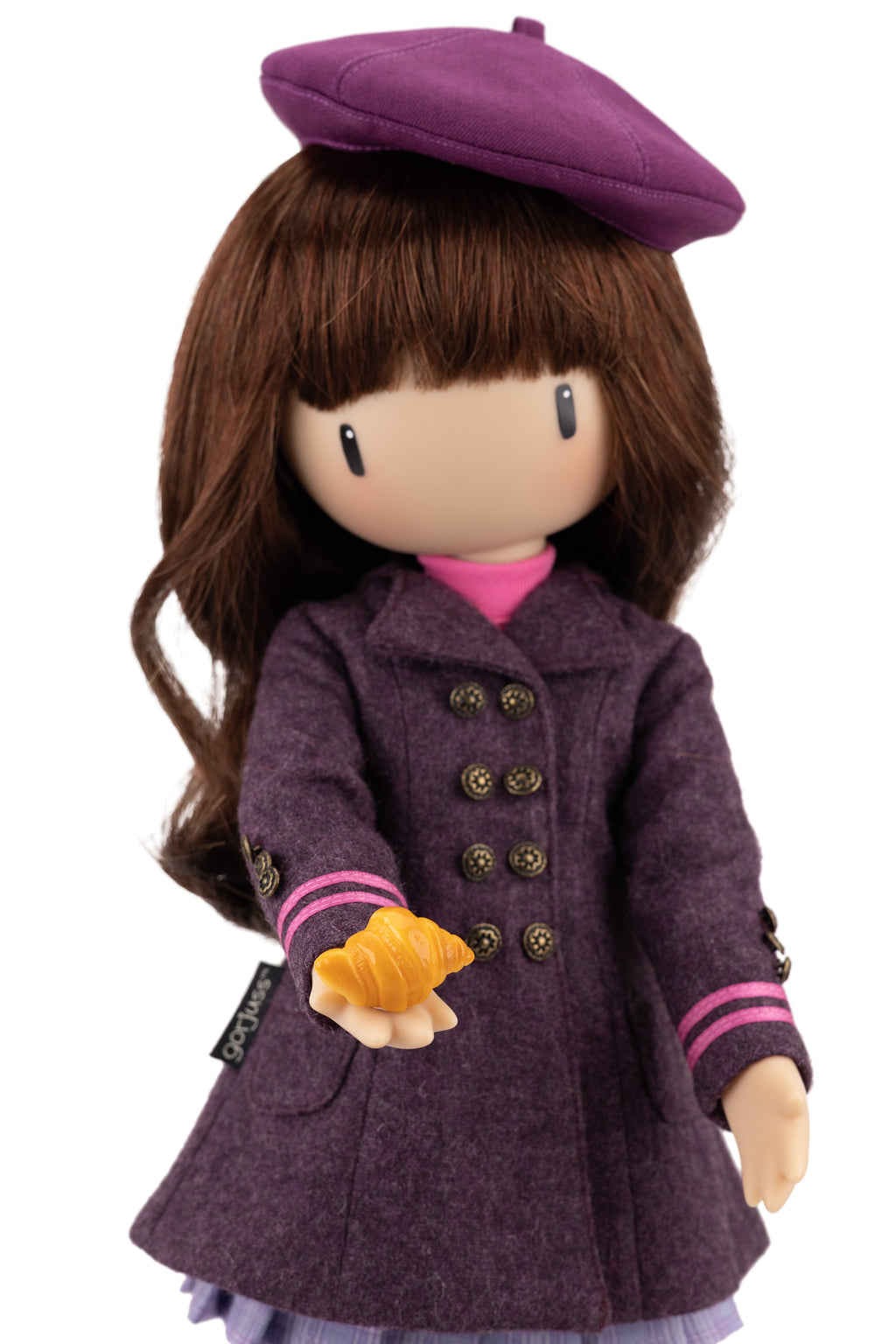 Doll wearing a purple coat and beret holding a croissant on a white background