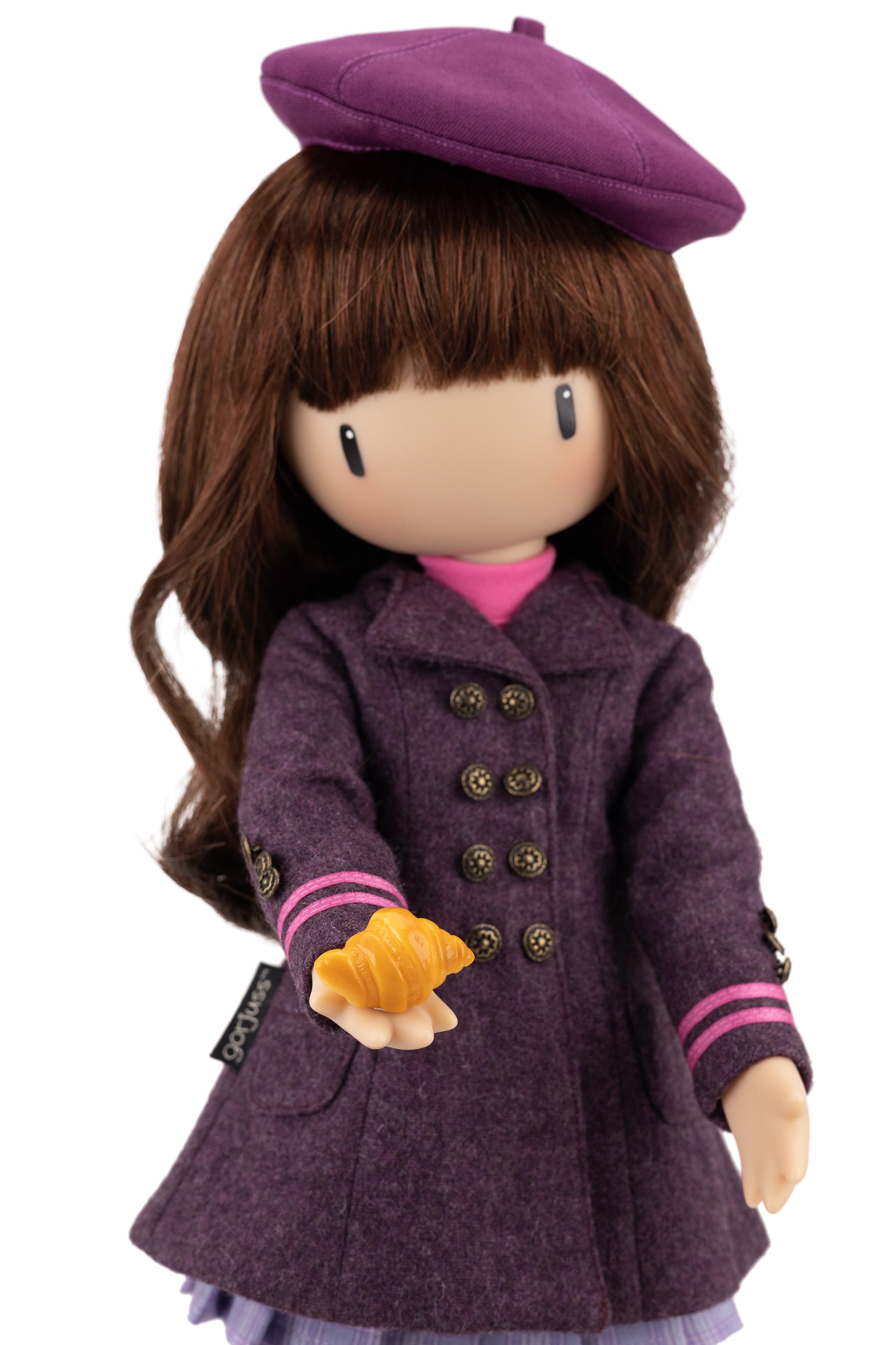 Doll wearing a purple coat and beret holding a croissant on a white background