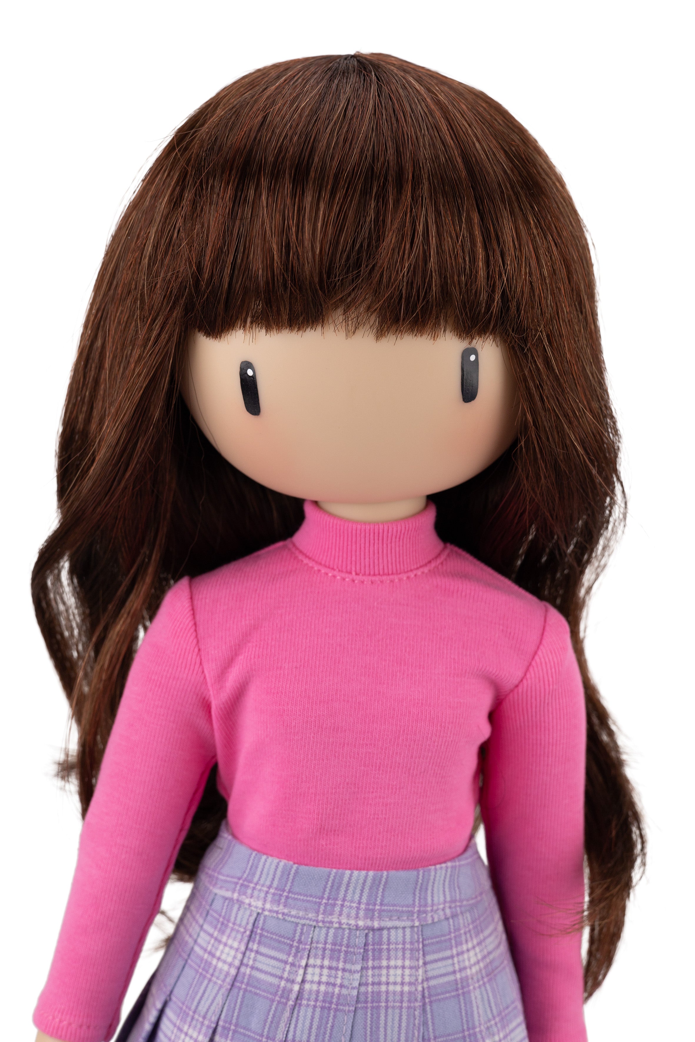 Doll with long brown hair wearing a pink sweater and plaid skirt on a white background