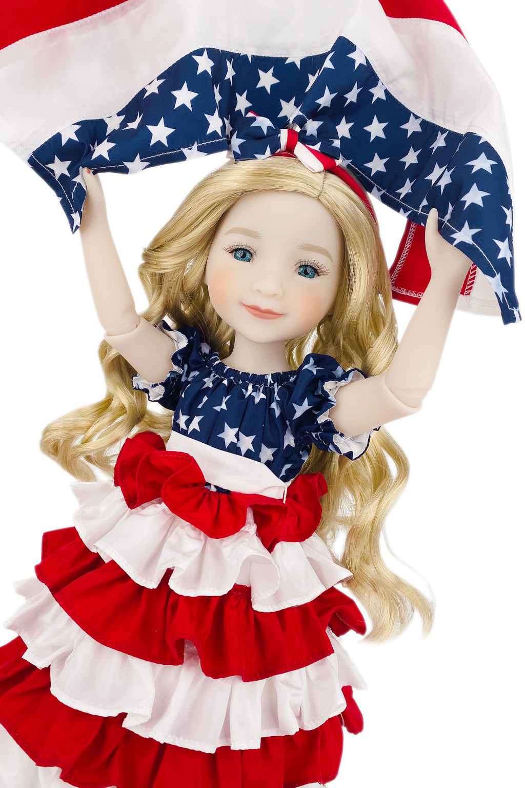 Doll wearing a patriotic outfit with an American flag-themed dress and accessories.
