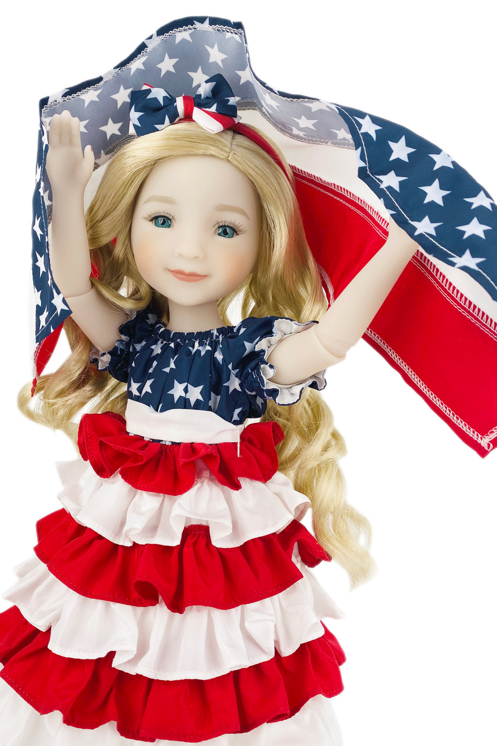 Doll wearing a patriotic dress with a matching headband, holding an American flag.