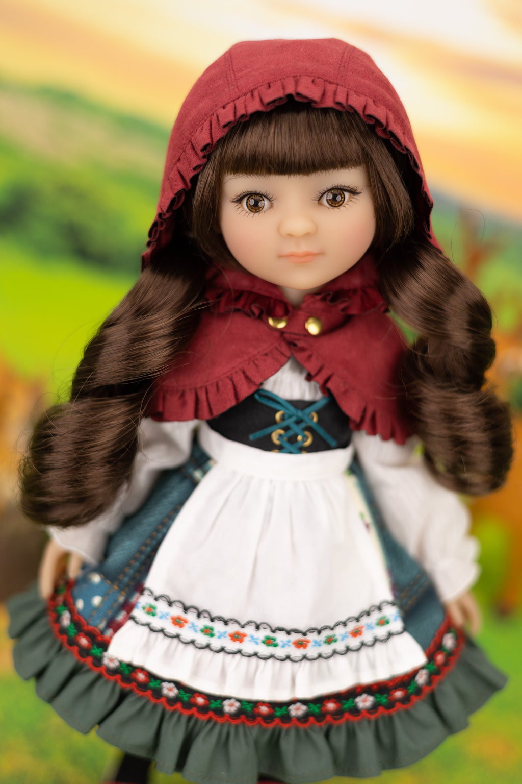 Doll in traditional outfit with a red hood against a blurred natural background