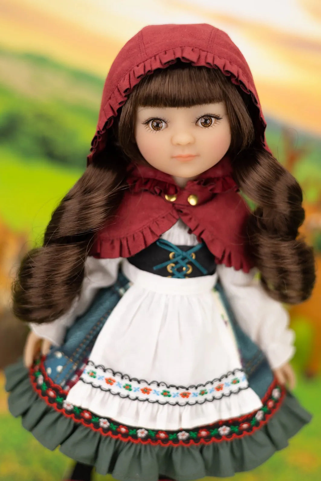 Liitle Red Riding Hood inspired collectible doll Rosie in traditional outfit with a red hood against a blurred natural background