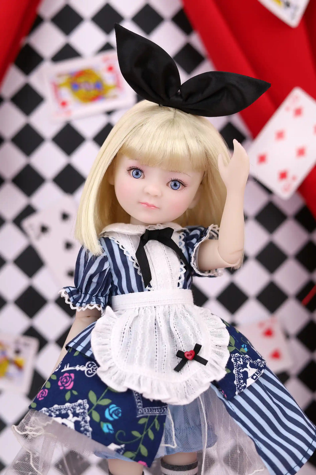Doll with blonde hair and a black bow, wearing a maid outfit against a checkered background.