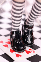 Black shiny shoes with striped socks on a checkered floor