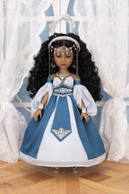 Doll in a blue and white dress with jewelry against a decorative background