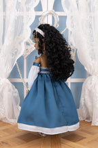 Doll in a blue dress with a tiara against a decorative white curtain background
