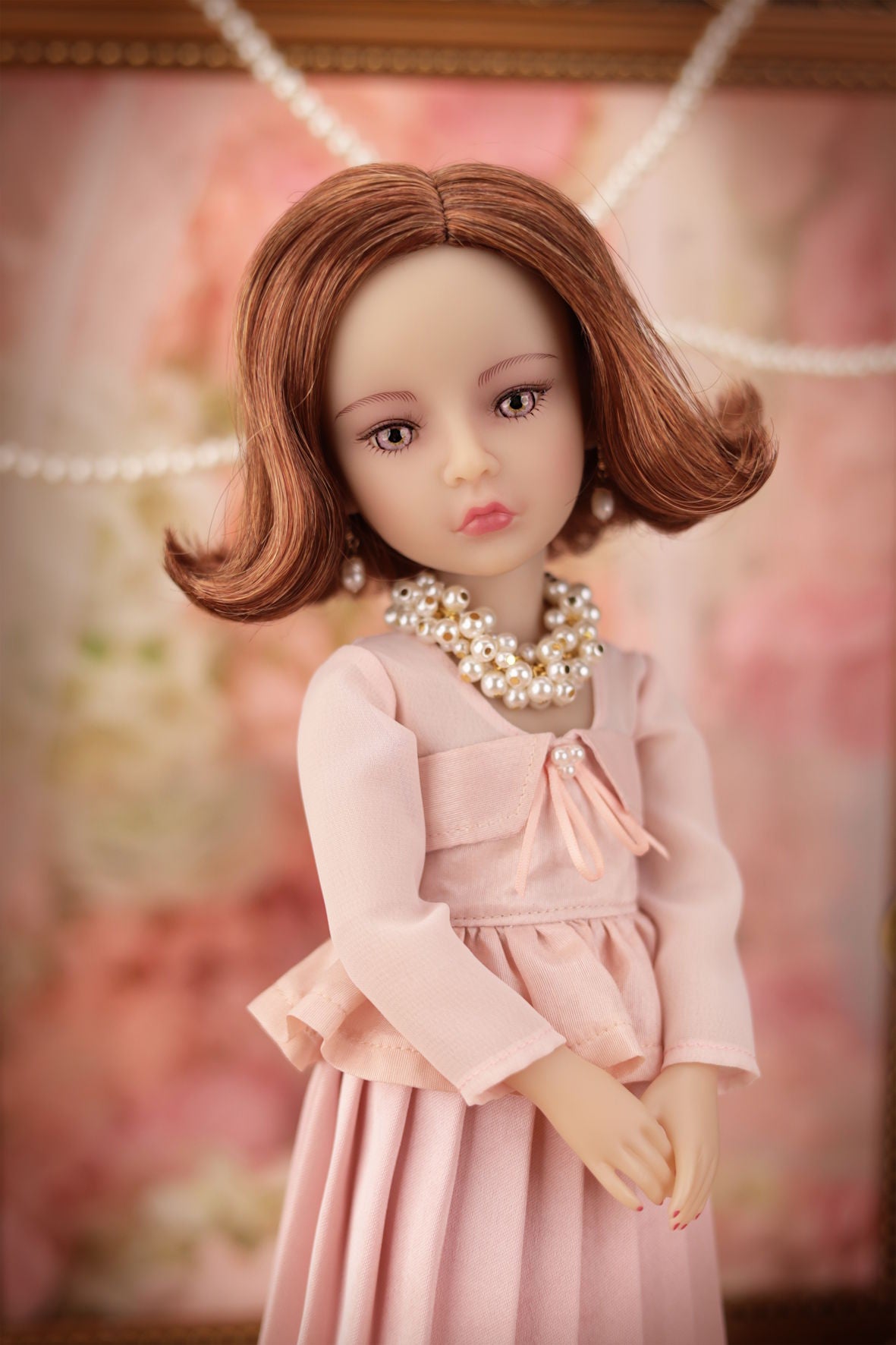 Lou in a pink dress with a blurred floral background