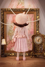 Lou in a pink outfit with a decorative frame and clock in the background