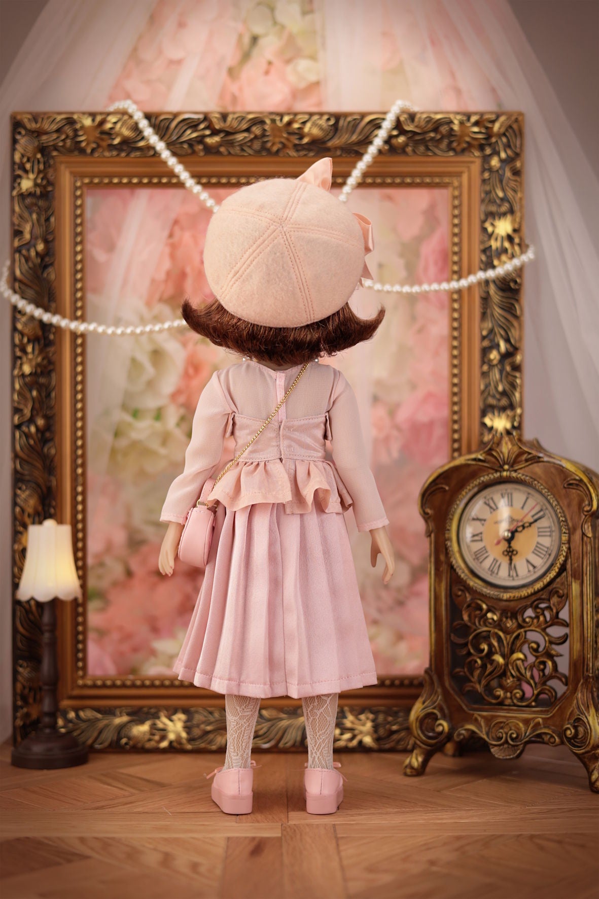 Lou in a pink outfit with a decorative frame and clock in the background