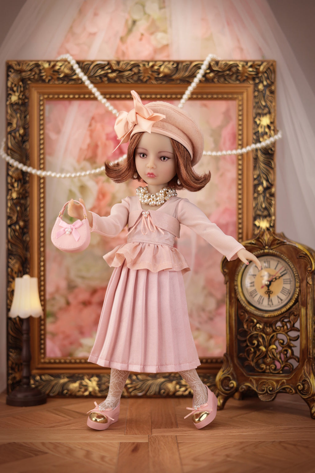 Lou in a pink dress standing in front of an ornate gold frame and clock.