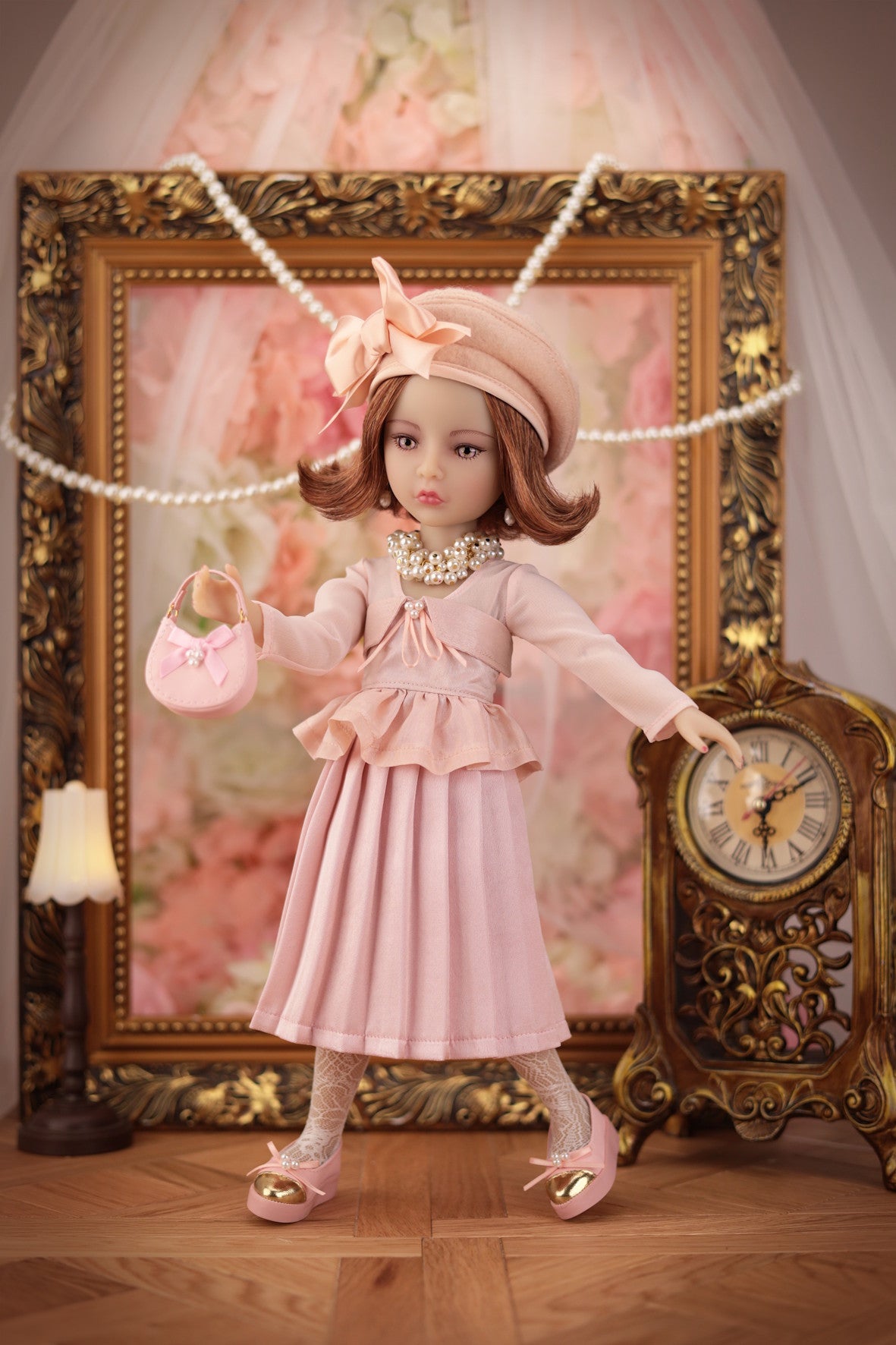 Lou in a pink dress standing in front of an ornate gold frame and clock.