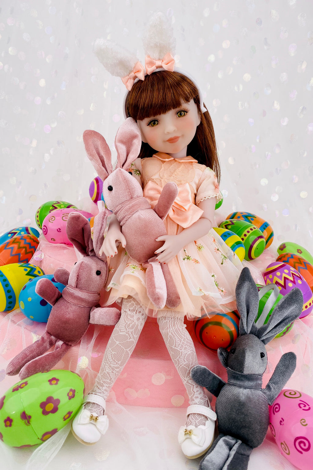 Doll with Easter-themed plush bunnies and eggs on a white background