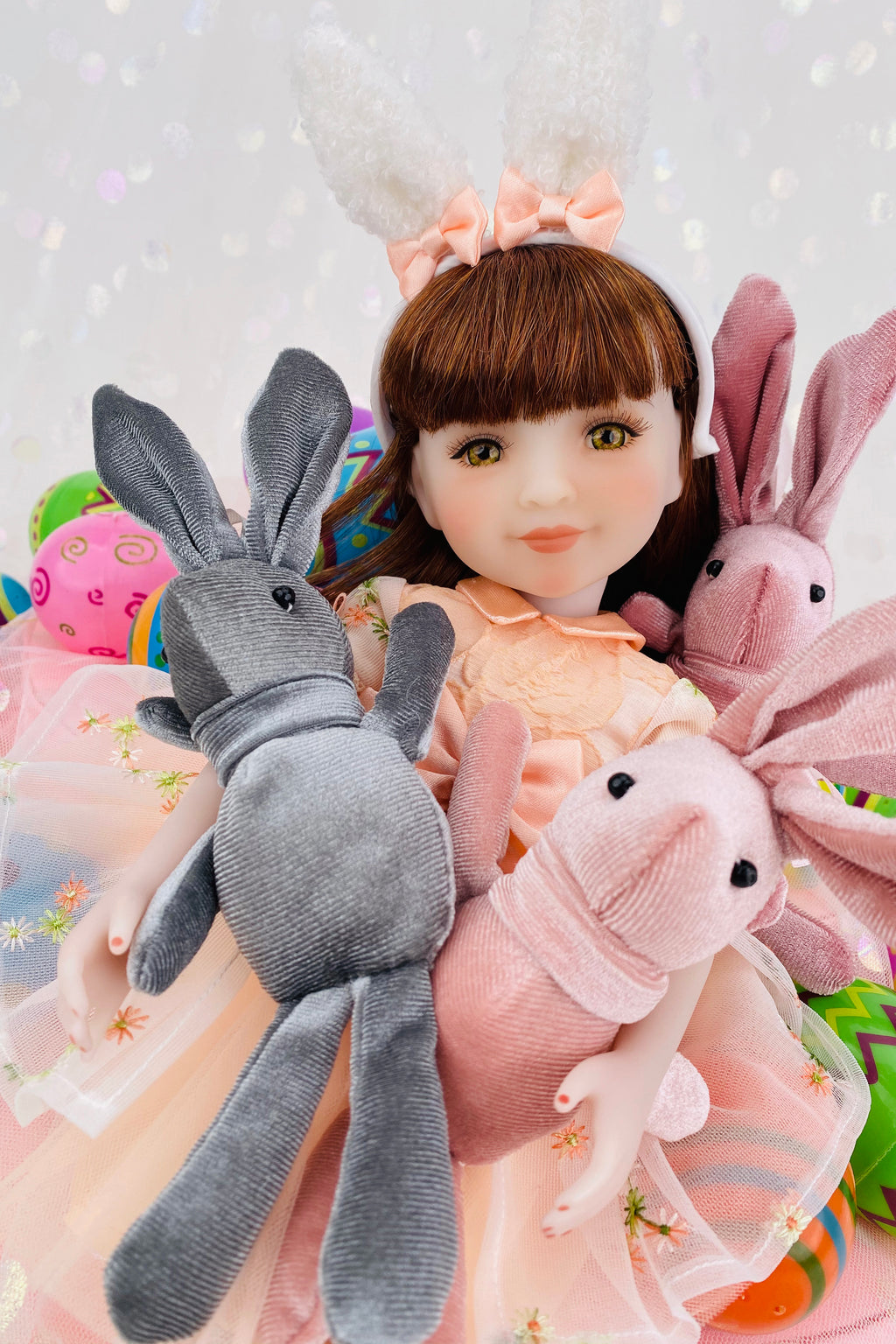 Doll with bunny ears surrounded by plush toys on a light background