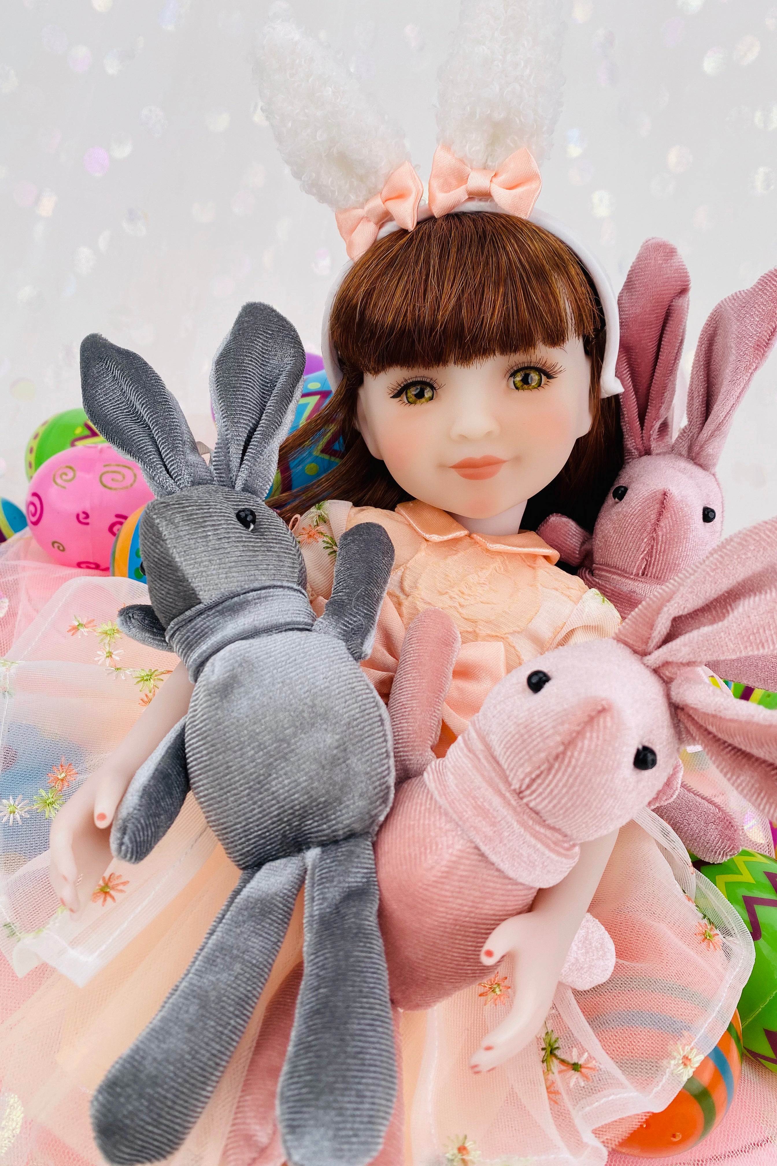 Doll with bunny ears surrounded by plush toys on a light background