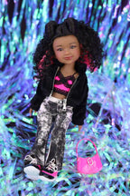 Doll with stylish outfit and pink handbag on a colorful tinsel background
