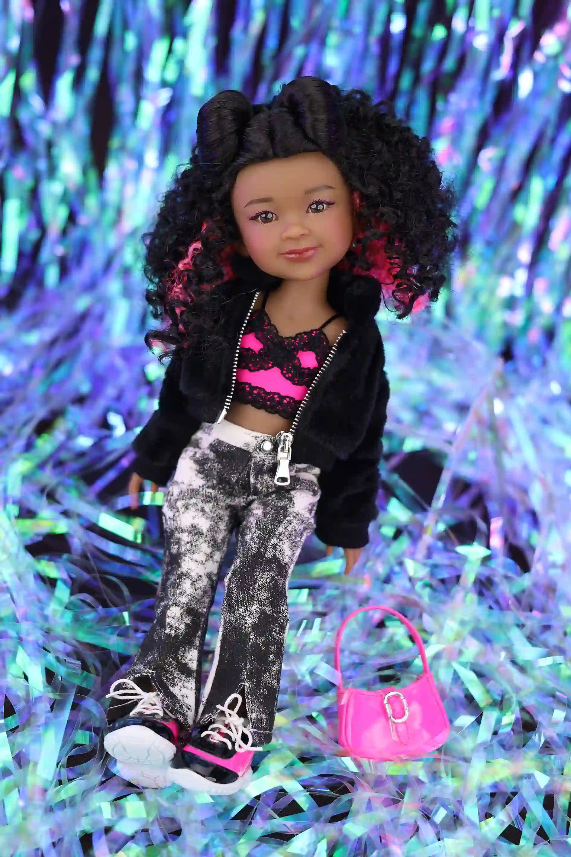 Doll with stylish outfit and pink handbag on a colorful tinsel background
