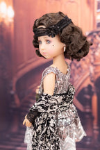Doll in a vintage-style dress with a decorative headband against a blurred background